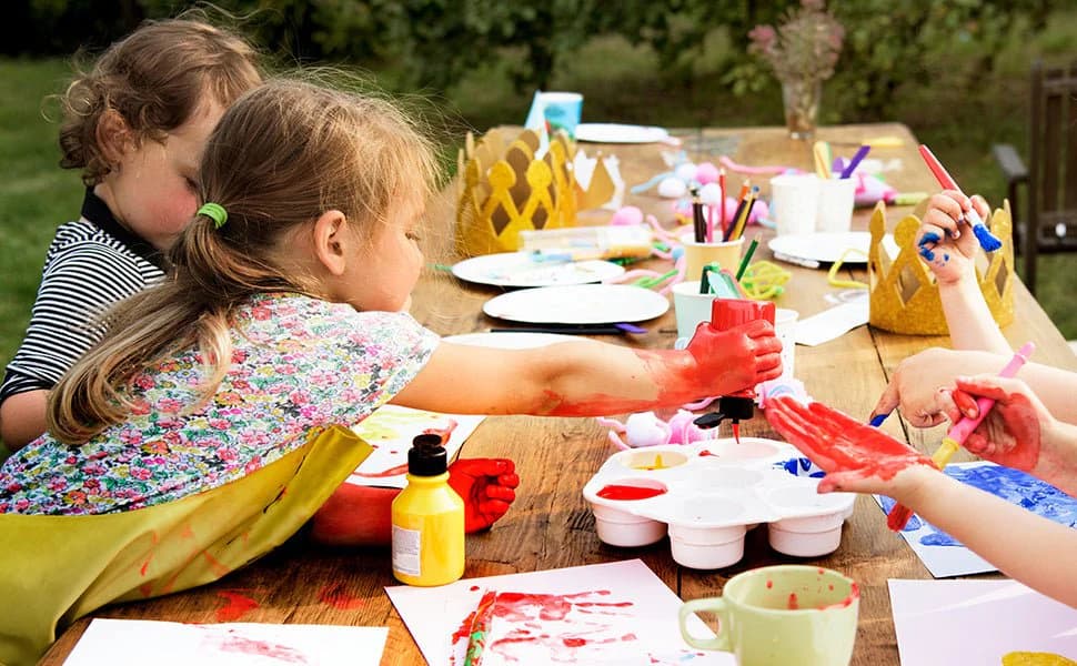Children painting at a wooden outdoor table
